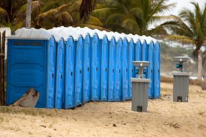 line of porta potties in a beach with a hand washing station
