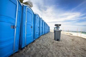 line of porta potties in a beach with a hand washing station